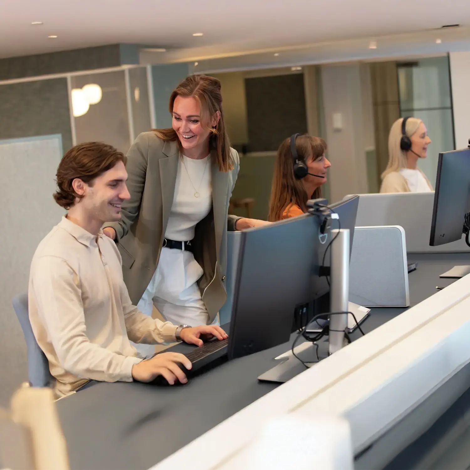Et bilde av fire personer foran datamaskiner på et kontor som jobber med kundeservice