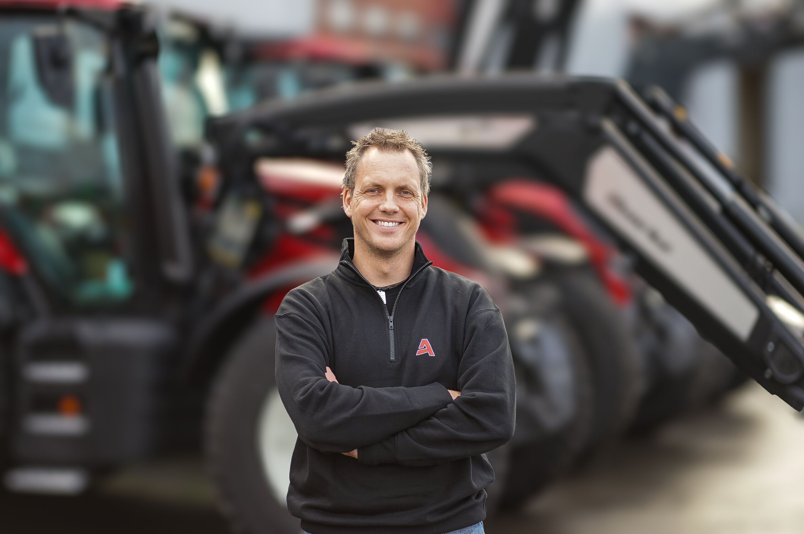 Kristian Sveen, ny selger hos Akershus Traktor Hamar, står smilende foran traktorer utenfor avdelingen.Kristian Sveen, ny selger hos Akershus Traktor Hamar, står smilende foran traktorer utenfor avdelingen.