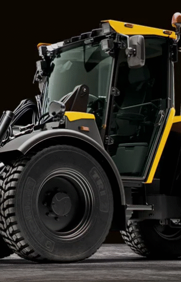 En gul Lundberg redskapsbærer i arbeid utendørs, omgitt av grønt landskap. Maskinen viser sin allsidighet og robuste design, og representerer pålitelighet og effektivitet for entreprenørarbeid året rundt.