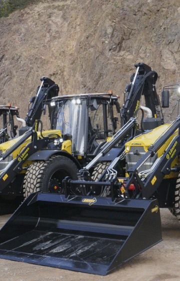 En Lännen grävlastare i arbeid på en byggeplass, viser sin kraft og fleksibilitet som både gravemaskin og hjullaster.